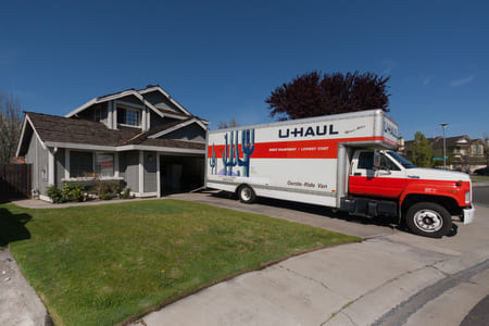 a large uhaul truck parked in a driveway in front of a single family home