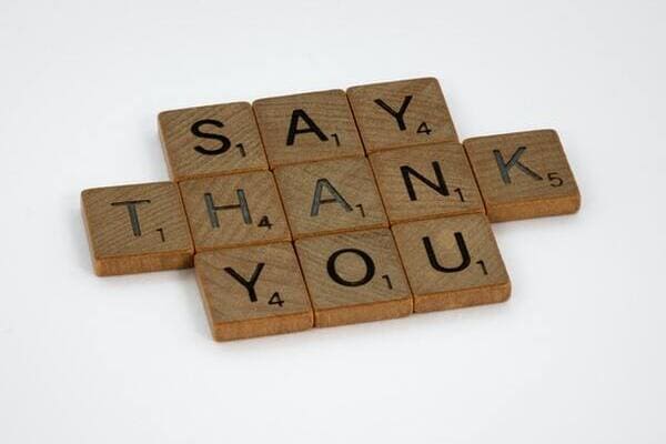 brown wooden scrabble blocks on white surface that spell say thank you