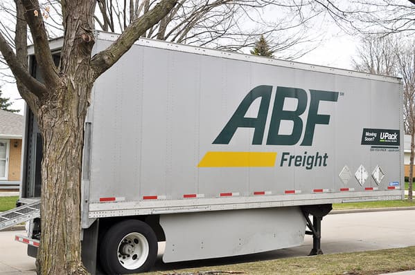 An ABF U-Pack moving trailer sits on a neighborhood street with the trailer ramp out