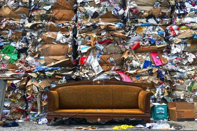 A brown couch sits in front of piles of trash