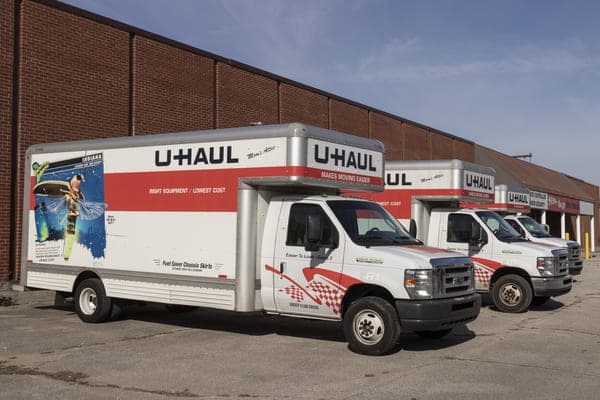 several U-Haul trucks are parked in a row outside of a warehouse