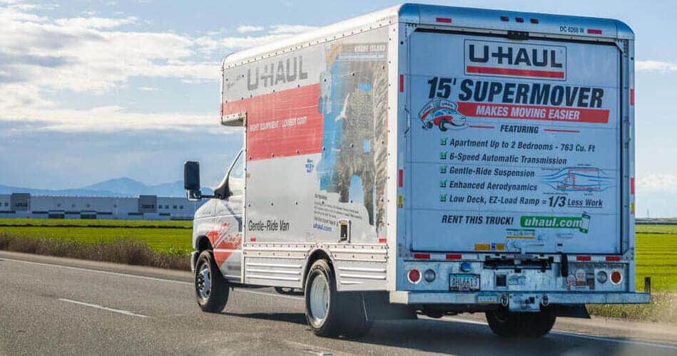 A U-Haul moving truck is driving down the road