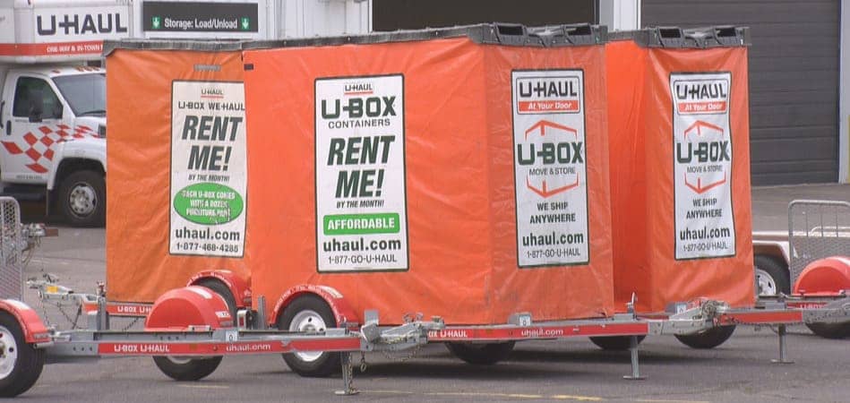 several U-Haul U-Box moving containers sit on trailers in a parking lot