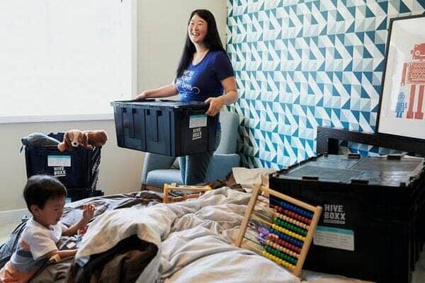 a woman is packing her bedroom into plastic moving boxes