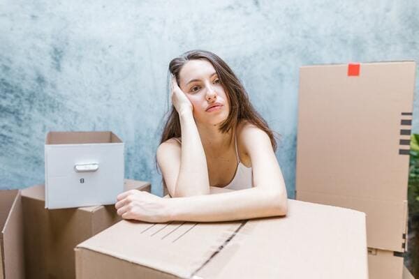 a woman is surrounded by moving boxes and appears stressed