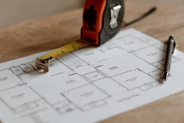 a tape measure sits on top of blueprints for a home