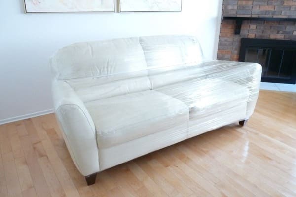 a white couch is covered with plastic wrap