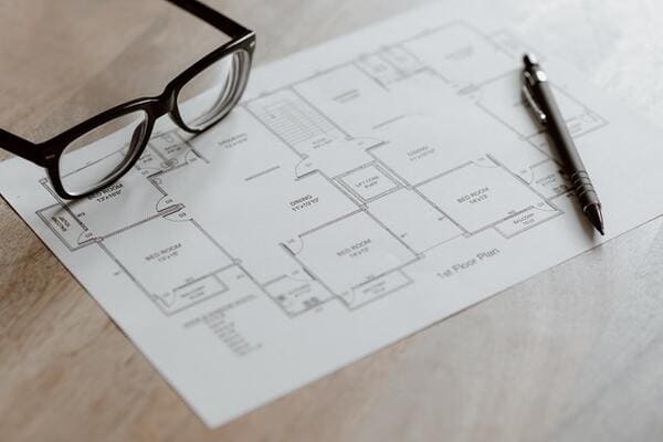blueprints for a house sit on a table with a pen and reading glasses