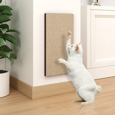 A white cat uses a scratch post attached to the wall