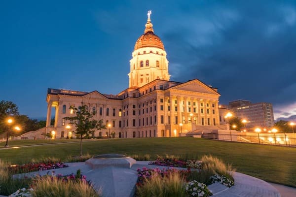 the kansas state capitol building lit up at dusk
