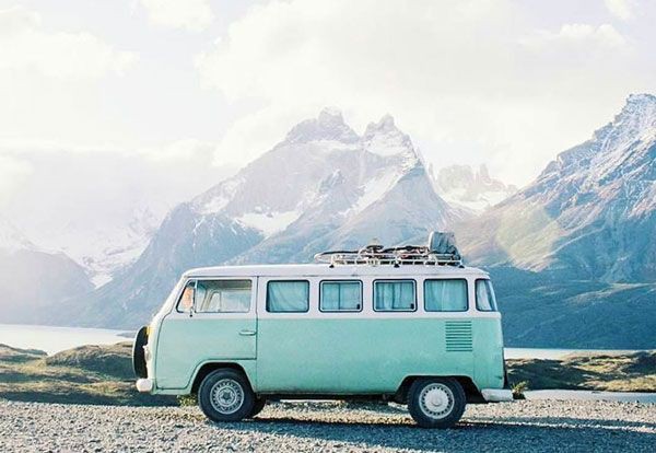 an old VW van parked with huge mountains in the background