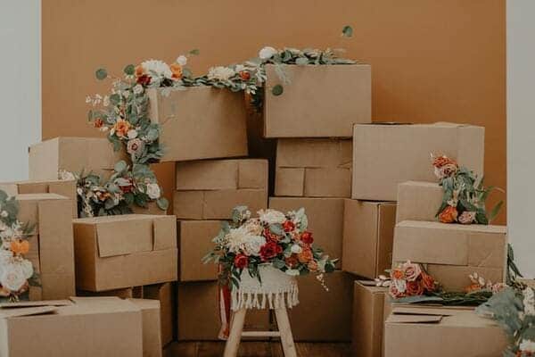 Many cardboard boxes are stacked on each other with plants and flowers on top of them