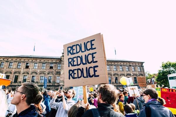 a group of protestors with one holding a sign that says 'reduce reduce reduce'
