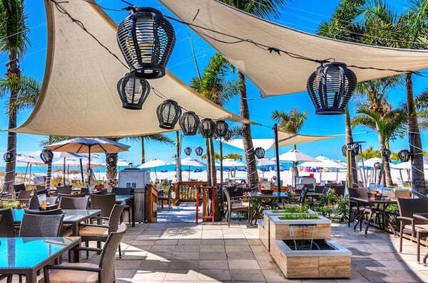 An exterior shot of dining tables and umbrellas on the beach at Bongos Beach Bar
