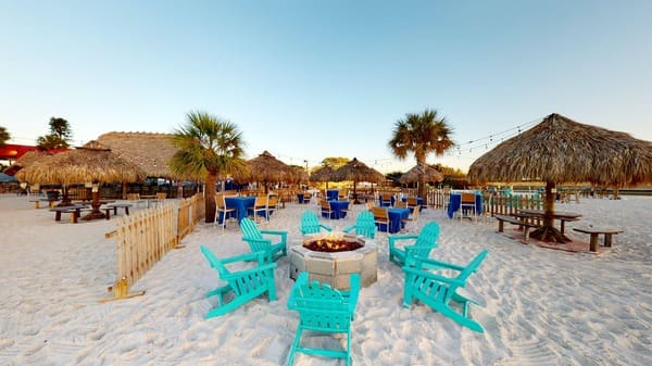 Adirondack chairs in a circle around a fire pit on the beach at Whiskey Joe's in Tampa