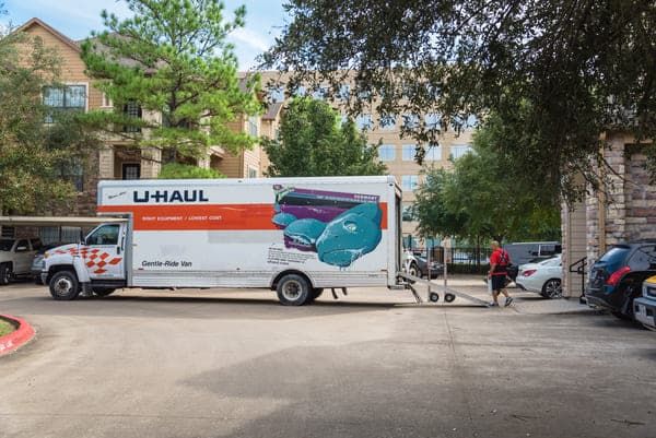 A U-Haul truck is parked outside of an apartment complex with the moving ramp out