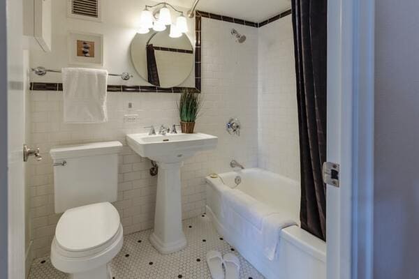 A bathroom with white tile walls and fixtures
