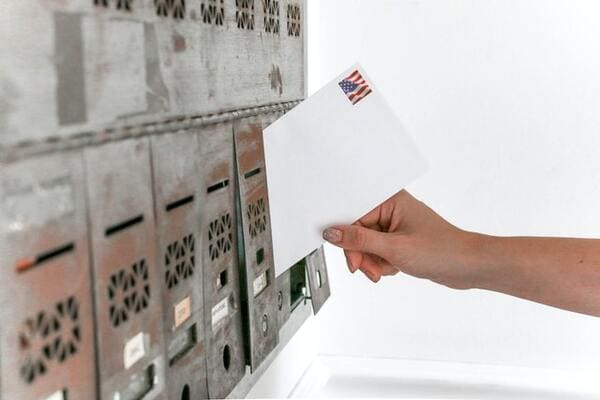 an envelope with a stamp is being placed into a mailbox
