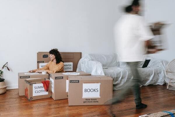 woman sitting on floor next to packed moving boxes