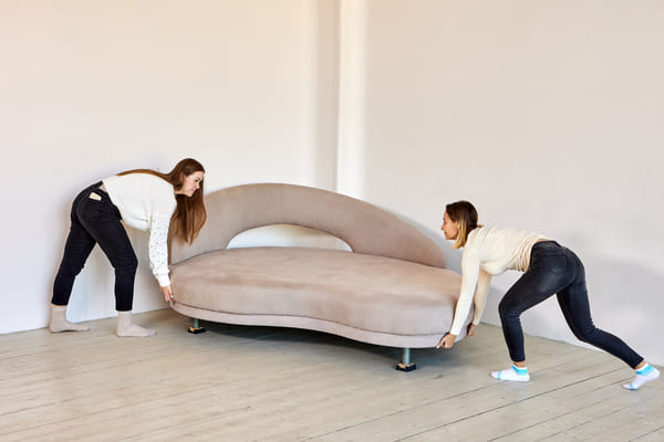 two women prepare to move a couch