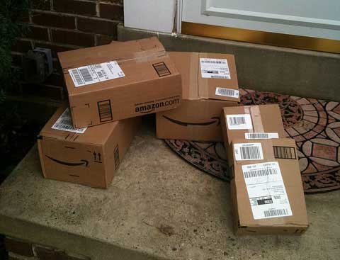 A pile of Amazon boxes sit on a doorstep