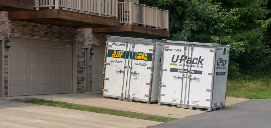 Two U-Pack ReloCube moving containers sit in a driveway